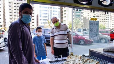 Mustaffa, eleven, waits for his bread to be baked with his uncle Abdul Qader outside the Naser Bader Bakery.