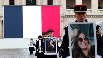 Presidential guards hold portraits of the French victims of the October 7 attack. AP