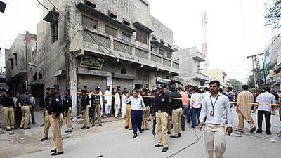 Pakistani security officials inspect the scene where nine Pakistan police officers were killed by Taliban gunmen in Lahore today.