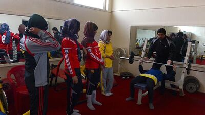 Afghan weightlifting coach Shahpoor supervises young women during a training session.