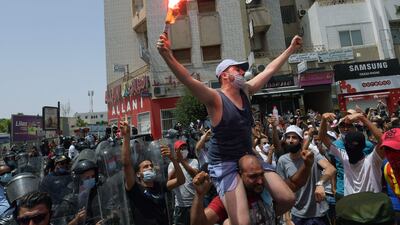 A Tunisian anti-government protester holds a flare during a rally in front of the Parliament in the capital Tunis on July 25, 2021. (Photo by FETHI BELAID / AFP)