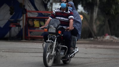 A man wearing a protective face mask to prevent the spread of the coronavirus disease (COVID-19) rides a motorcycle with his wife in Abu Kabir, north of Cairo, Egypt. Reuters