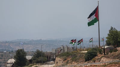 An Israeli flag flutters at a new Israeli settlement, behind Palestinian flags near Ramallah. Reuters