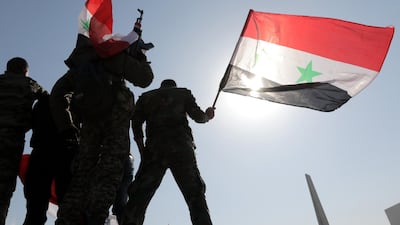 Syrian soldiers wave national flags during a gathering to show support for the government in Umayyad square in Damascus. Youssef Badawi / EPA