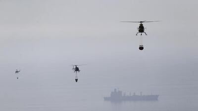 Helicopters pick up water from the Pacific Ocean to dump on the smouldering remains of houses after a fire burnt several neighbourhoods in the hills in Valparaiso city, north-west of Santiago. Ivan Alvarado / Reuters