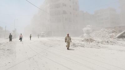 Syrians walk amid dust following a reported barrel-bomb attack by Syrian government forces on July 7, 2014 in the Tariq al-Bab neighbourhood in the northern city of Aleppo. The opposition Syrian National Coalition says that regime forces are preparing to launch a major assault on rebel-held areas of Aleppo. Zein Al Rifai/AFP Photo