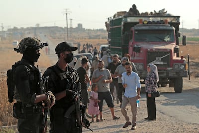 Security personnel stand guard as Syrian Kurds who were living in displacement camps in the city of Hasakah prepare to head back to the north-eastern border town of Ras Al Ain. AFP
