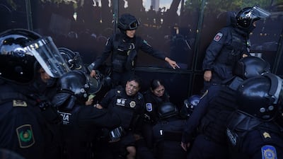 Police officers lean against a protection barrier in pain, surrounded by fellow officers, after being wounded by an explosive device thrown by protesters during clashes outside the attorney general's office, in Mexico City. The demonstrators were marching to mark the anniversary of the 2014 disappearance of 43 students of a teachers’ college in Iguala, Guerrero. AP