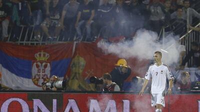 Albania's Ansi Agolli walks in a cloud of smoke after Serbia fans began throwing flares onto the pitch as tensions escalated on Tuesday during the Euro 2016 qualifying match. Marko Djurica / Reuters