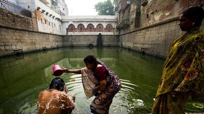 A man is bathed by a woman as another looks on, at the Hazrat Nizamuddin Baoli, the only one of Delhi's baolis to be fed by springs.