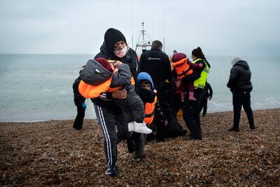 A migrant carries her children on the south-east coast of England after being rescued while crossing the English Channel. AFP