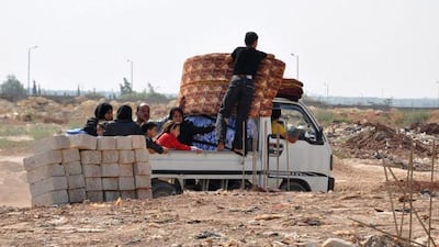 Syrian civilians flee the northern city of Aleppo during a lull in fighting between opposition forces and army troops on July 25, 2012. Battles raged through the night in several districts of Syria's second largest city to which the regime had rushed reinforcement, after rebels launched an all-out assault for control of the country's commercial hub on July 20. Arabic graffiti on the police station's entrance reads "Assad's Syria". AFP PHOTO / PIERRE TORRES
