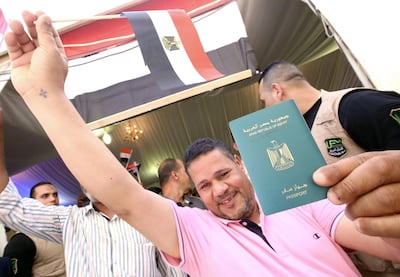 An Egyptian national in Kuwait waves a flag and displays his passport as he prepares to vote at the Egyptian embassy in Kuwait City. AFP