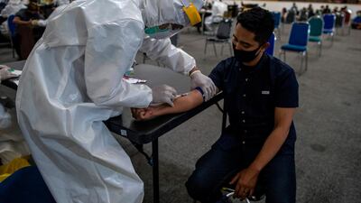 An Indonesian medical staffer takes a blood sample from a youth after he violated the large-scale social restrictions at a police headquarter in Surabaya. AFP