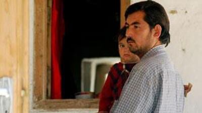 Aminullah holds his daughter in his home where his pregnant wife died in a gun battle.
