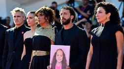 Director Kaouther Ben Hania stands beside actor Motaz Malhees, who holds a portrait of the slain Palestinian girl at the premiere of The Voice of Hind Rajab in Venice. AFP