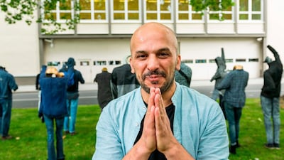 Syrian artist Khaled Barakeh poses in front of his installation called 'The Muted Demonstration.'
