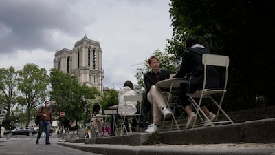 People sit outdoors at a restaurant terrace near Notre Dame cathedral in Paris, France. Cafe and restaurant terraces reopened this week after a pandemic shutdown of more than six months. AP Photo