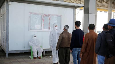Members of the medical team check the temperature of Iraqi men, following the coronavirus outbreak, at the entrance checkpoint of South Mosul, Iraq. Reuters