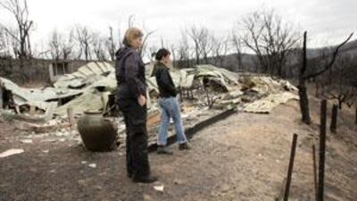 Residents Kylie Gill and Lisa Clemance inspect their house in the aftermath of the deadly bushfire.