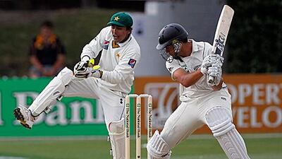 Adnan Akmal, left, fields behind the stumps as New Zealand batsman Ross Taylor looks on.