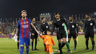 Barcelona’s Lionel Messi holds the hand of Afghan boy Murtaza Ahmadi on the pitch before the start of a friendly football match against Saudi Arabia’s Al Ahli FC in the Qatari capital Doha. Karim Jaafar / AFP