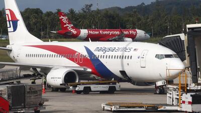 An AirAsia plane is about to take off behind a boarding Malaysia Airlines plane on the resort island of Phuket, southern Thailand. Barbara Walton / EPA