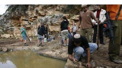 Israeli settlers, protected by armed men, shovel the ground to divert water from a spring in the Palestinian West Bank village of Karawa Bani Hassan, south of Nablus in 2010.
