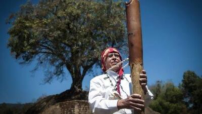 An indigenous man holds a musical instrument during a Maya ceremony in Iximche, Chimaltenango, Guatemala.
