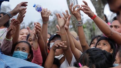 Filipinos scramble for bottled water in a town near the Taal volcano on Sunday, January 19. Many poor families living near the volcano have been warn they must leave the area as the chance of an eruption remains high. Aaron Favila / AP