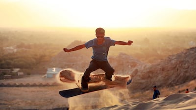 A member of the Afghanistan Snowboarding Federation practices sandboarding for the first time in the province of Kapisa in Afghanistan. EPA