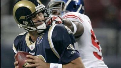 The Rams quarterback Marc Bulger shields the ball from the New York Giants' defensive end Justin Tuck during their defeat.