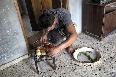Mohamed Fawda watches over onions, and tomatoes roasting over a small electric coil burner at his mother's home in Twam, in the northern area of the Gaza Strip .(Photo by Heidi Levine For The National).