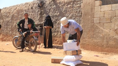 An aid worker with supplies as a local looks on. Millions will be at a risk of starvation if the flow of aid stops.