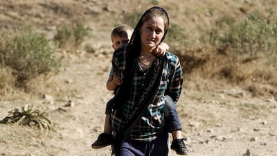 A Yazidi refugee fleeing Iraq woman carries her son on her back at the Turkish-Iraqi border on August 17, 2014. Ulas Yunus Tosun/EPA