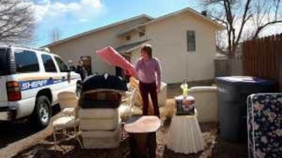 A sheriff's deputy supervises as a landlady clears out a home in Lafayette, Colorado, after the tenants were evicted.