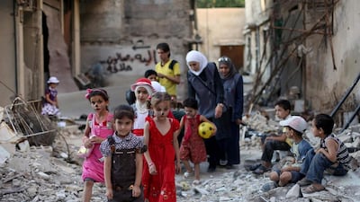 Syrian children walk amid destruction on the outskirts of Damascus ahead of the Eid Al Fitr holiday. Amer Al Mohibany / AFP