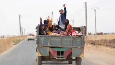 Civilians gesture while riding on a tractor as they withdraw from the border town of Tal Abyad, Syria. Reuters