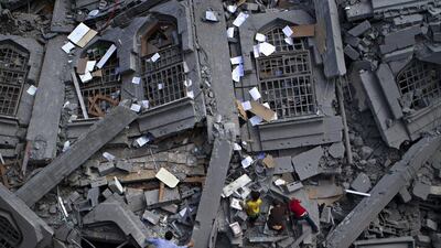 Palestinians collect religious books from the rubble of Al Qassam Mosque in the Gaza Strip’s Nuseirat camp on July 9, a day when Israeli warplanes carried out 30 airstrikes.