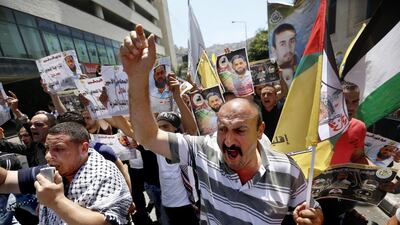 Protesters hold portraits of Palestinian prisoner Mohammad Allan, held in an Israeli jail, during a support rally calling for his release in the West Bank city of Nablus, on August 14. EPA