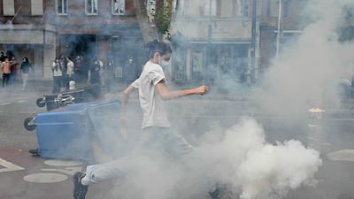 A protester about to kick a smoking tear-gas canister during a riot in Toulouse. AFP