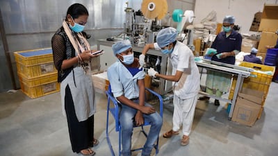 An Indian health worker administers the Covishield vaccine to a worker at the factory of a face-mask manufacturer on the outskirts of Ahmedabad. AP