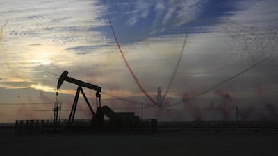 An oil pump works as Al Fursan, the aerobatics demonstration team of the UAE Air Force, performs during the Bahrain International Airshow in Sakhir, Bahrain. Hasan Jamali / AP Photo