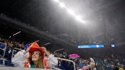 A fan takes cover from the rain in the Louis Armstrong Stadium during a match between Kevin Anderson of South Africa and Diego Schwartzman of Argentina. AP Photo