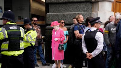 A woman holds a cutout of Queen Elizabeth II outside St Paul's Cathedral. AP