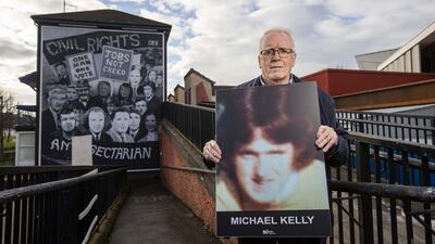 John Kelly, brother of Michael Kelly who was killed on Bloody Sunday in Derry's Bogside in 1972, holds an image of his brother beside the Civil Rights mural in Derry, Northern Ireland. PA