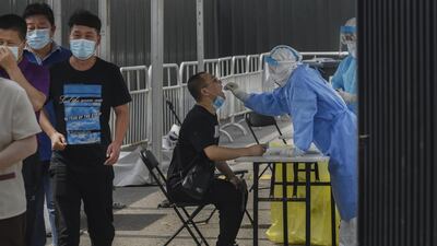 A Chinese pandemic control worker wears a protective suit as she performs a nucleic acid swab test for Covid-19 on a man at a government testing site in Beijing, China. Getty Images