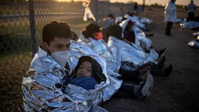 Dustin, an asylum-seeking migrant from Honduras, holds his son Jerrardo, 6, as they wake at sunrise next to other migrants, in La Joya, Texas, US, after crossing the Rio Grande from Mexico on rafts. Reuters