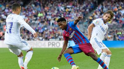 Barcelona forward Ansu Fati tries to evade challenges from Real Madrid forward Lucas Vazquez (L) and midfielder Luka Modric. AFP