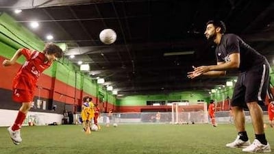 Anas Bukhash helps a boy practise heading at Ahdaaf Sports Club in Dubai.